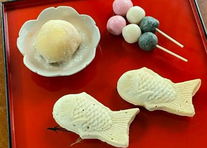 Mochi, dango, and taiyaki laid out on a lacquer serving traying at a Japanese dessert cooking class.